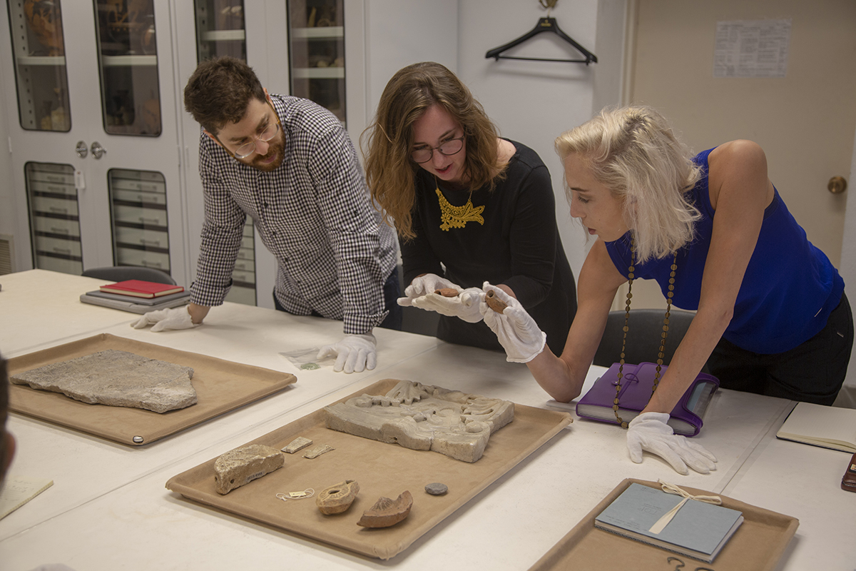 From left, Students Omri Matarasso (Princeton), Sarah Porter (Harvard), and Rebekah Haigh (Princeton) inspect pilgrimage ampullae. Photo by Julie Clack, Princeton University.