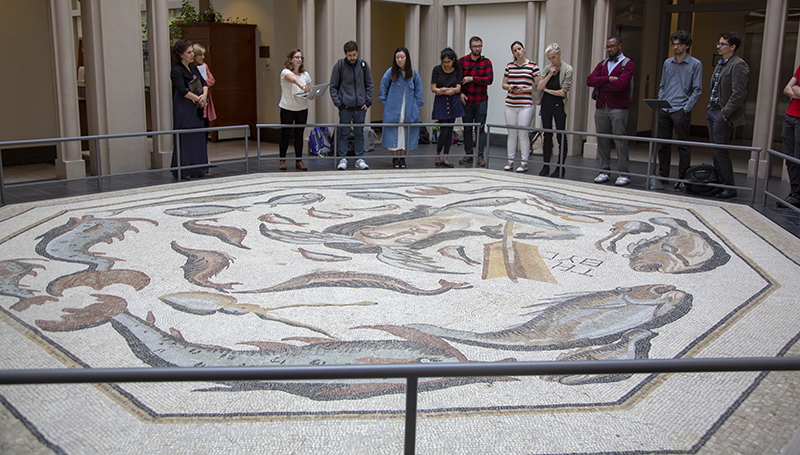 Harvard PhD candidate Sarah Porter presents her research on the Tethys mosaic in the lobby of a Harvard Business School administrative building. Photo by Julie Clack, Princeton University.